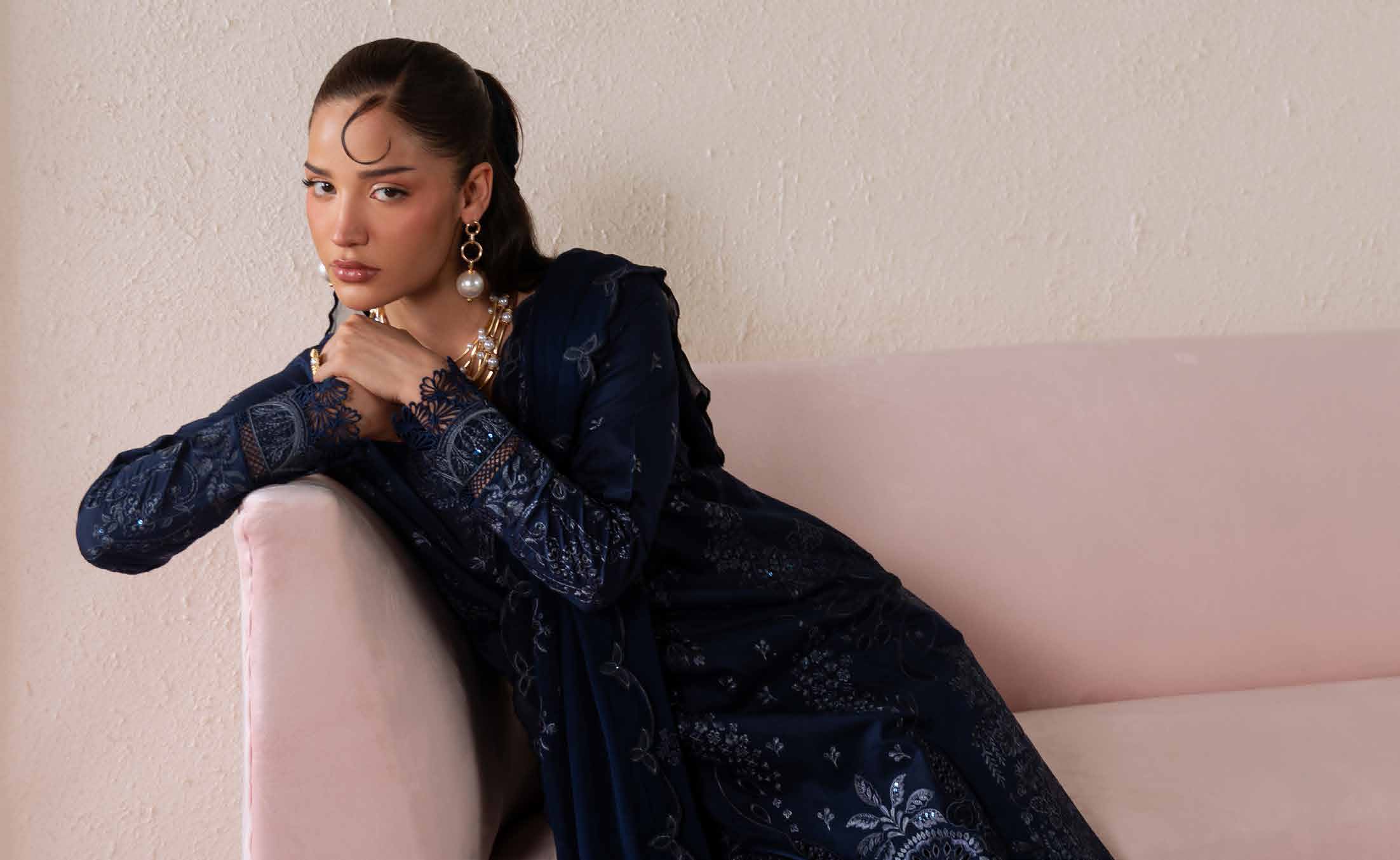 Model wearing a navy embroidered Pakistani outfit in a styled campaign setting